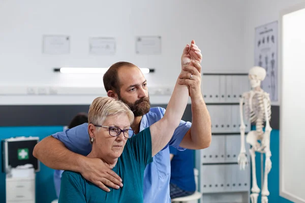 Chiropraticien étirant les muscles du bras de la femme âgée avec blessure — Photo