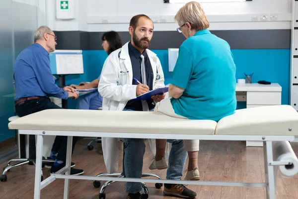 Paziente anziano che discute con il medico sull'osteopatia — Foto Stock