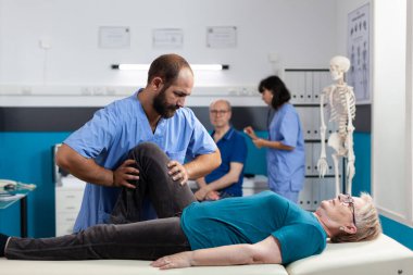 Kayropraktik uzmanı hastanın dizindeki baskıyı azaltmaya çalışıyor.