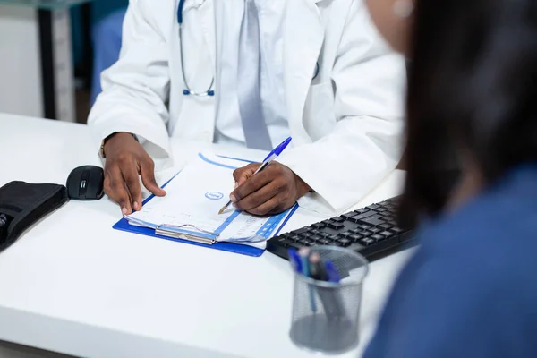 Closeup of african american pediatrician doctor writing healthcare treatment — Stock Photo, Image