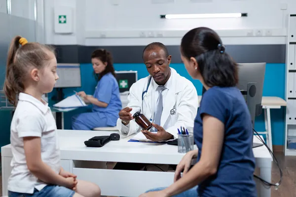 Médico pediatra afroamericano explicando tratamiento antibiótico al paciente madre —  Fotos de Stock