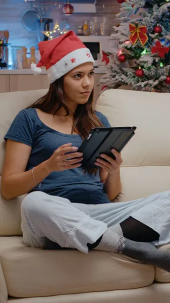 Slavnostní osoba pracující na tabletu a dívající se na televizi na Štědrý den — Stock fotografie