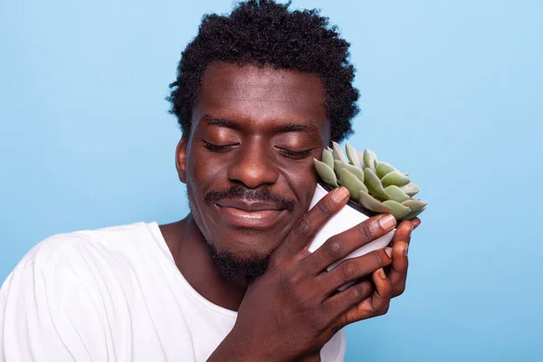 Ειρηνικός άνθρωπος κρατώντας μικρή κατσαρόλα με το φυτό και χαμογελώντας — Φωτογραφία Αρχείου