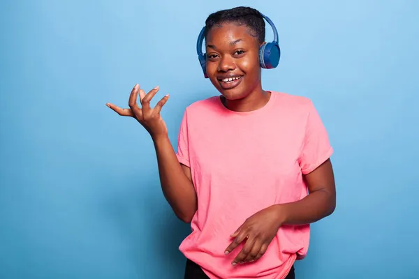 Retrato de una joven afroamericana con auriculares sonriendo a la cámara —  Fotos de Stock