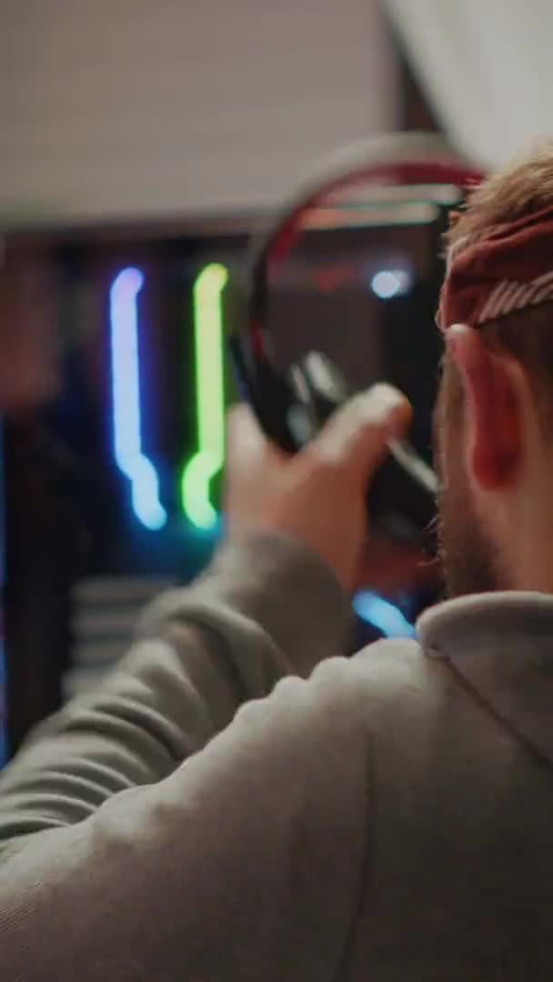 수직 영상: 온라인 비디오 게임에서 슈팅 게임을 하는 사람에게 초점을 맞춘 남성 게이머 — 비디오