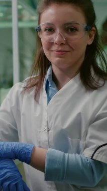 Dikey video: Genetik olarak değiştirilmiş organizmayı analiz eden gülümseyen biyolog kadın portresi