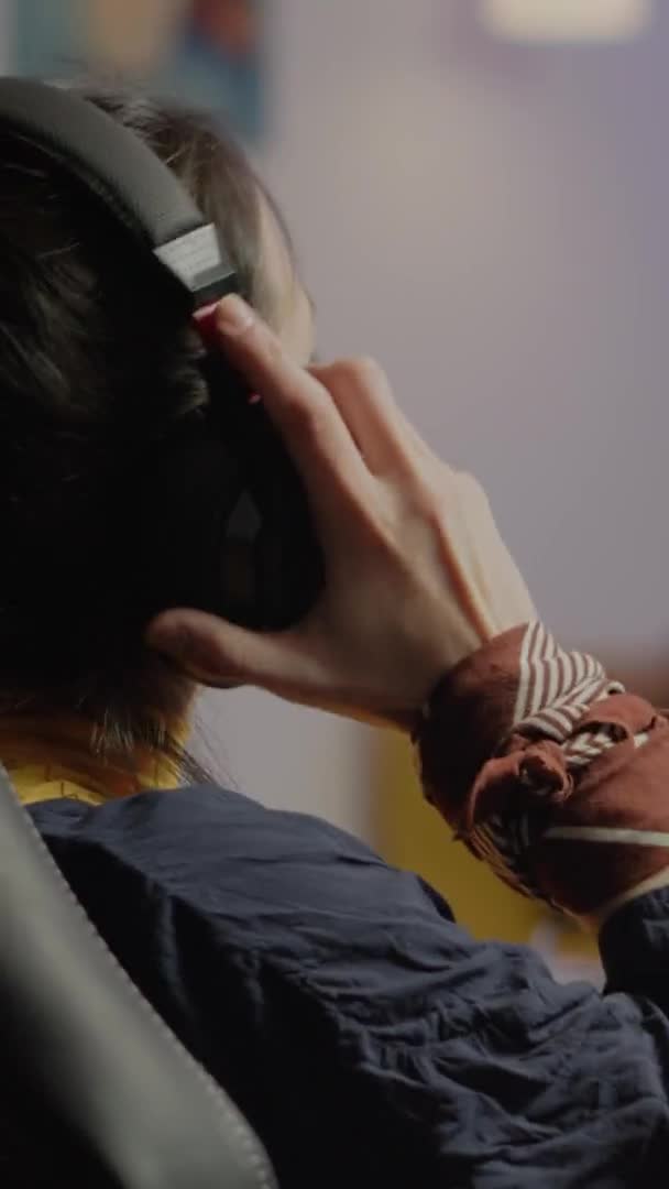 垂直ビデオ:集中女性ゲーマーはヘッドセットに置く机の上に座って — ストック動画