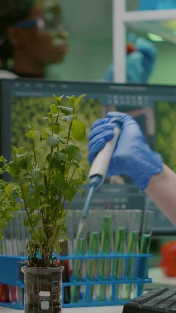 Pionowe wideo: Biolog używający mikropipety umieszczającej roztwór genetyczny w probówce — Wideo stockowe