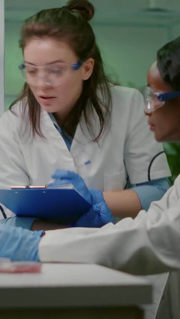 Video verticale: Due college che controllano campioni di carne vegana che scrivono competenze biotecnologiche — Video Stock