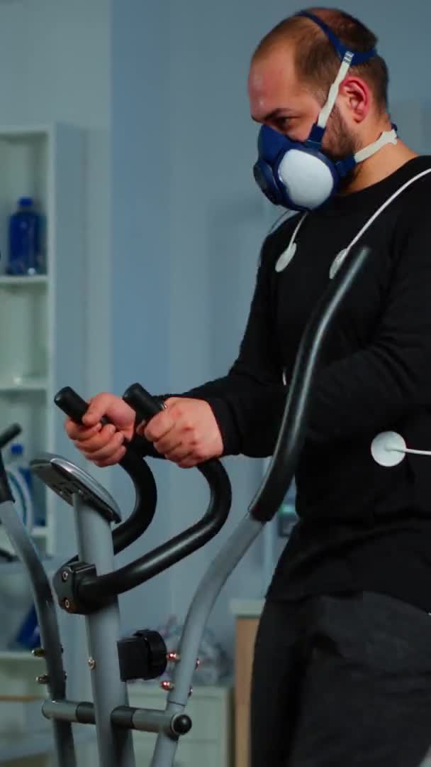 Vertical video: Doctor asking patient about his health while sportsman running on cross trainer — Stock Video