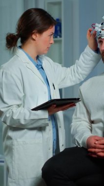 Dikey video: Beyin dalgaları tarama kulaklığıyla nörolojik sandalyede oturan adam