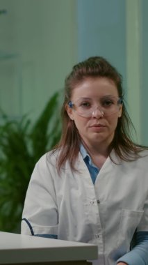 Dikey video: Beyaz önlüklü botanikçi kadın çevrimiçi video görüşmesi sırasında kimyacı ekibi
