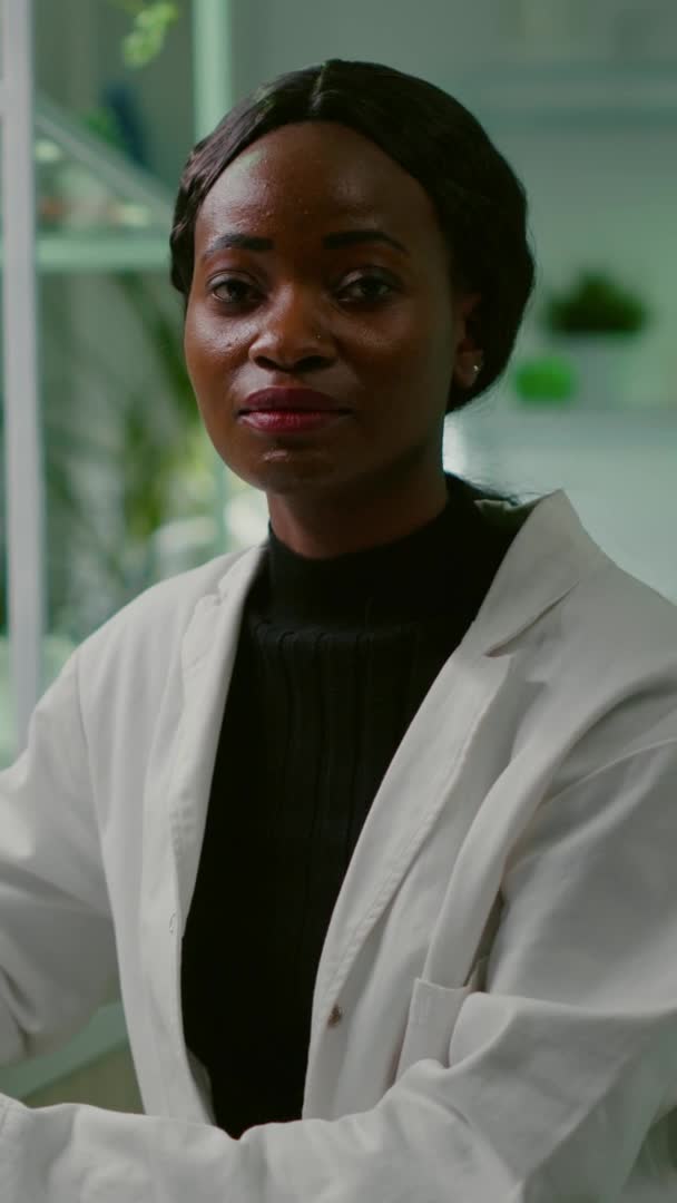 Vertikal video: Närbild av afrikansk biolog kvinna tittar in i kameran — Stockvideo