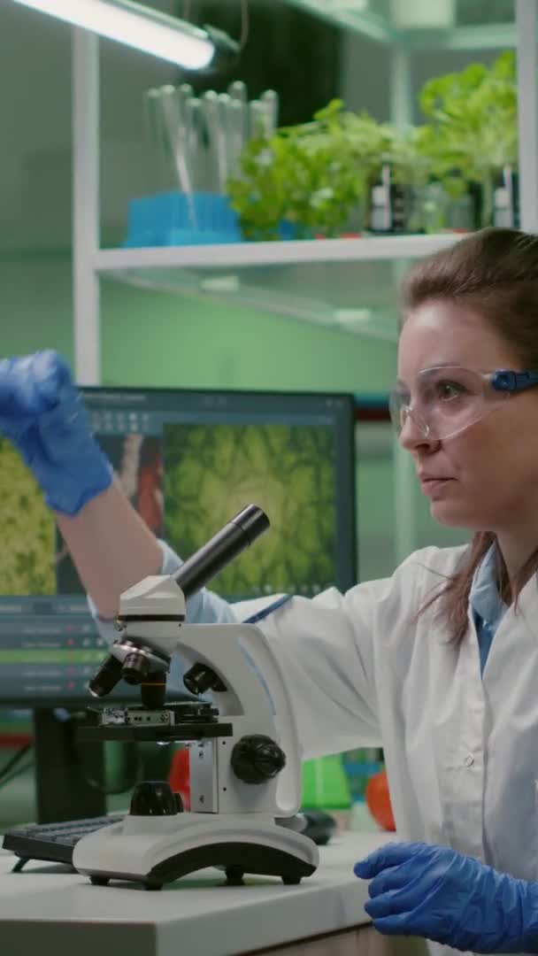 Vertical video: Biologist scientist looking at test sample using microscope — Stock Video