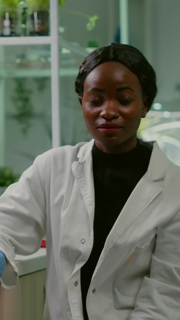 Pionowe wideo: Pov afrykańskiej kobiety siedzącej przy biurku w laboratorium farmaceutycznym — Wideo stockowe