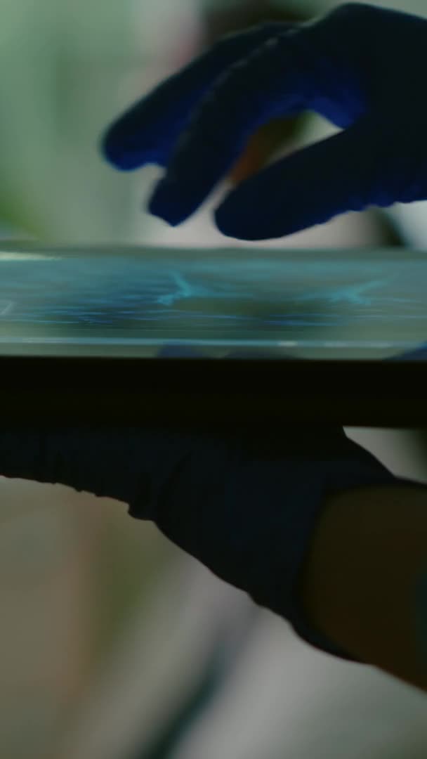 Вертикальное видео: Ученая-химик проверяет образец ДНК с помощью планшета — стоковое видео