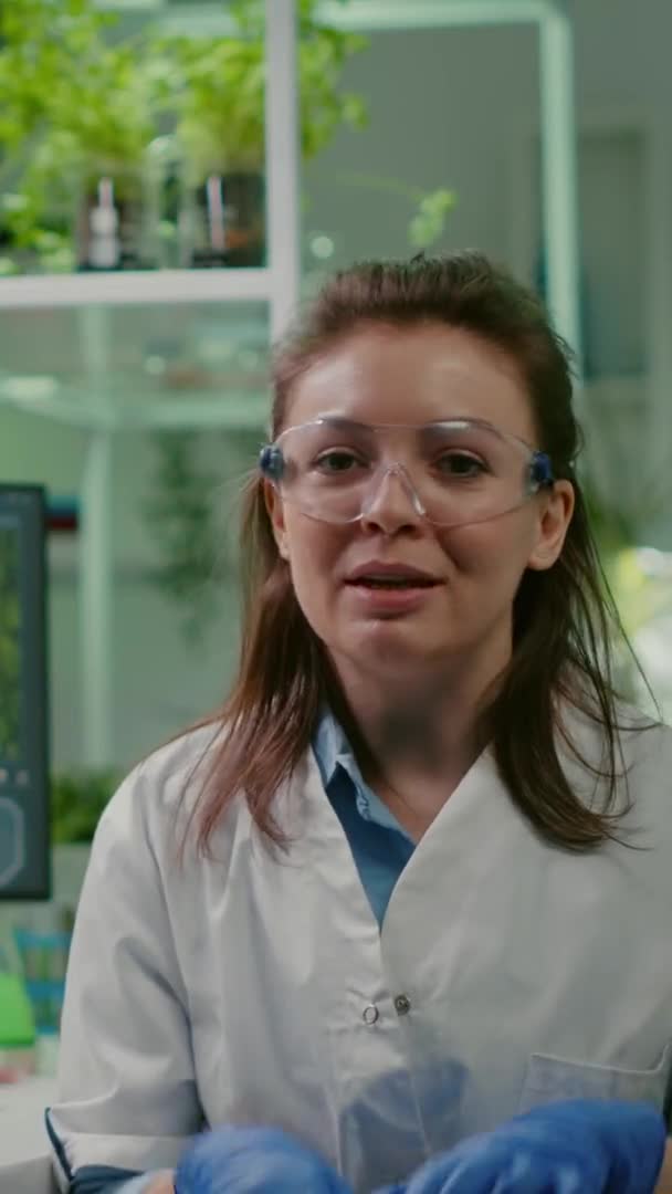 Vídeo vertical: Pov de mujer química en bata blanca analizando con el equipo de biólogos — Vídeo de stock