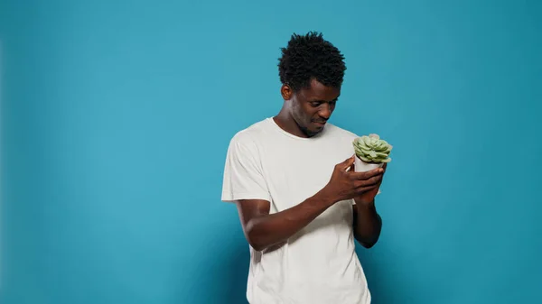 Ung man som håller blomkruka med grön planta — Stockfoto