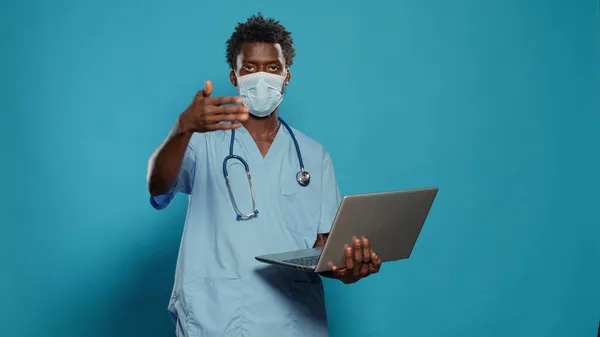 Homem enfermeira vestindo máscara facial e segurando laptop — Fotografia de Stock