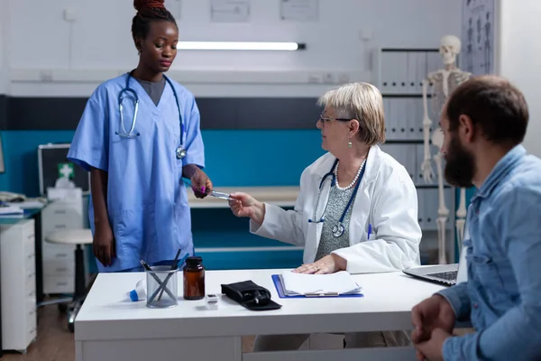 Enfermera afroamericana dando resultados de rayos X al médico para cita con el hombre — Foto de Stock