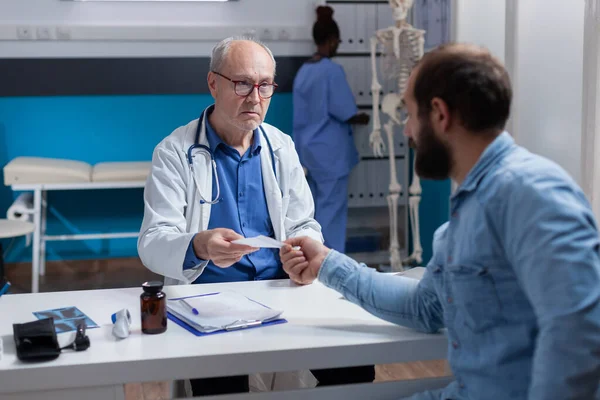 Specialist giving prescription paper to sick patient at checkup visit — Stock Photo, Image