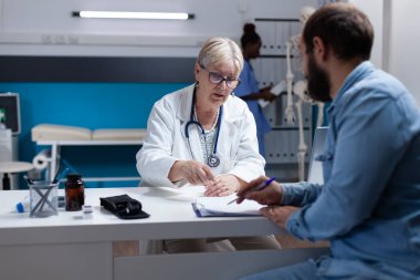 Sağlık ziyaretindeki hasta doktor ve randevu için muayene kağıtlarını imzalıyor.