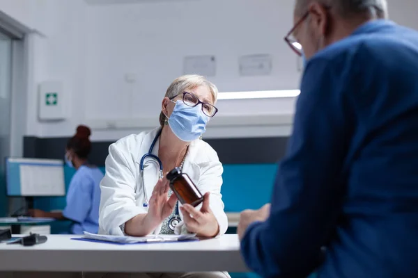 Arzt zeigt Flasche Pillen, die er alten Patienten während der 19-jährigen Pandemie geben soll — Stockfoto