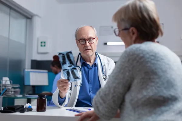 Arzt erklärt alten Patienten bei Konsultation Röntgenergebnisse und Diagnose — Stockfoto