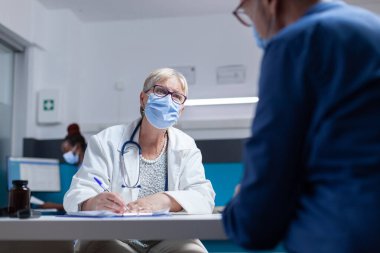 Salgın sırasında bir adamla sağlık kontrolünde doktor randevu belgeleri imzaladı