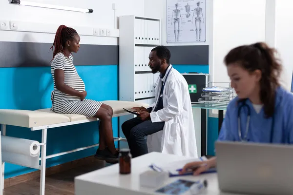 Médico com tablet digital consulta paciente grávida — Fotografia de Stock