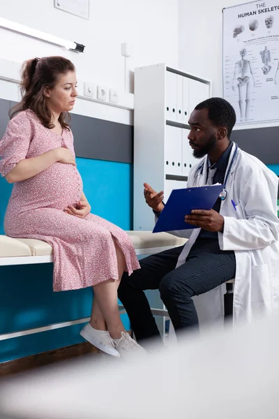 Afrikalı Amerikalı sıhhiyeci kabinedeki hamile kadına danışmanlık yapıyor. — Stok fotoğraf