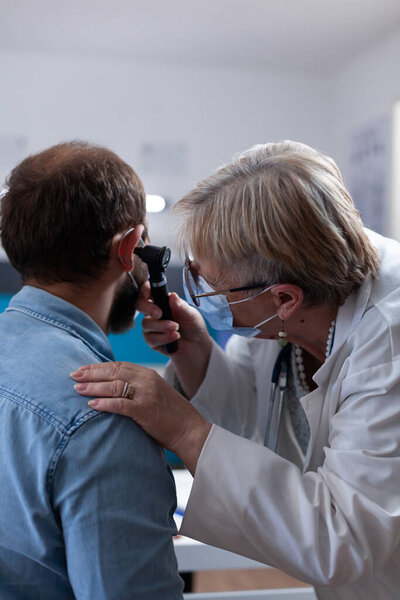 Крупный план медика, держащего отоскоп для обследования уха у пациента