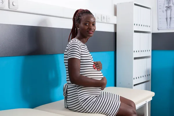 Portrait of cheerful woman expecting child in medical care office — Stock Photo, Image