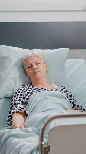 Idősebb nő intravénás infúziós zsákkal alszik a kórházi kórteremben. — Stock Fotó