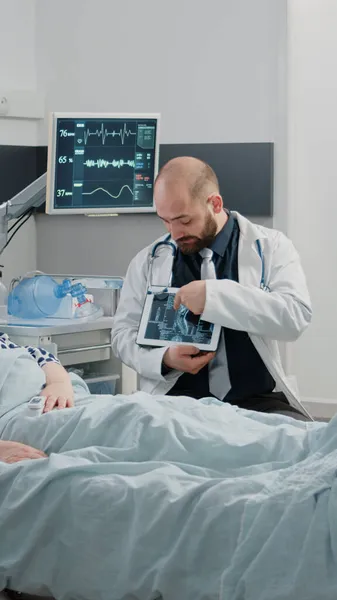 Läkare som förklarar röntgenskanning resultat på tabletten till äldre patienter — Stockfoto