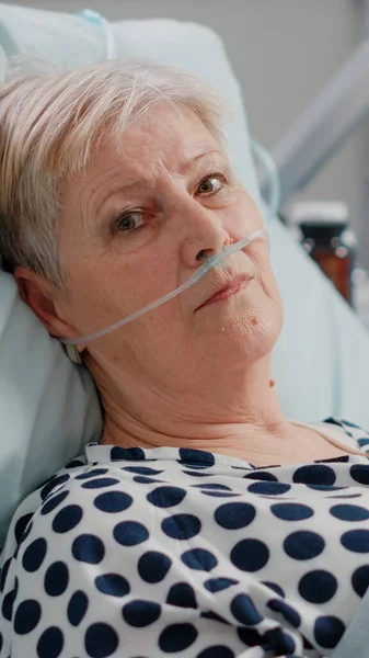 Ritratto di donna anziana con tubo di ossigeno nasale disteso a letto — Foto Stock