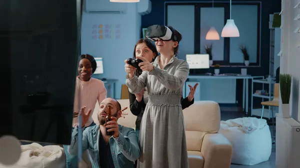 Vrouw met joystick en vr bril terwijl werkmaten juichen — Stockfoto