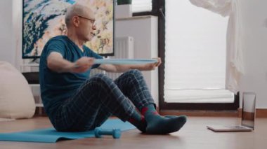 Yaşlı yetişkin direniş bandıyla streç egzersizi yapıyor.