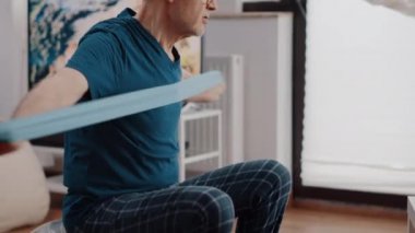 Egzersiz yapmak için direniş bandını çeken yaşlılara yaklaş