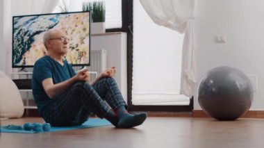Kıdemli adam lotus pozisyonunda oturuyor ve meditasyon yapıyor.