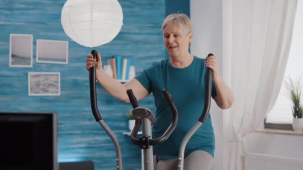自宅で固定自転車で引退した女性の訓練 — ストック動画