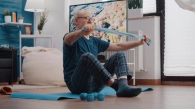 Yaşlı adam esnemek ve çekmek için direnç bandı kullanıyor.