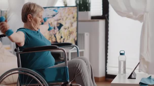 Oude vrouw met een handicap met behulp van halters om te oefenen — Stockvideo