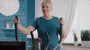 Emekli bir kadının evde bisiklete binmesine yakın.