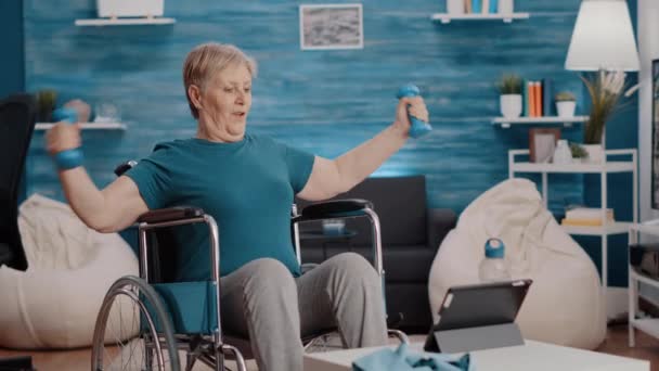 Älterer Erwachsener sitzt im Rollstuhl und macht Übung mit Gewichten — Stockvideo