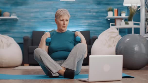 Mujer jubilada usando mancuernas para entrenar los músculos de los brazos — Vídeos de Stock