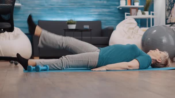 Senior femme levant les jambes pour faire de l'exercice physique sur tapis de yoga — Video