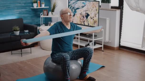 Starší muž používající pásku odporu k fyzickému cvičení — Stock video