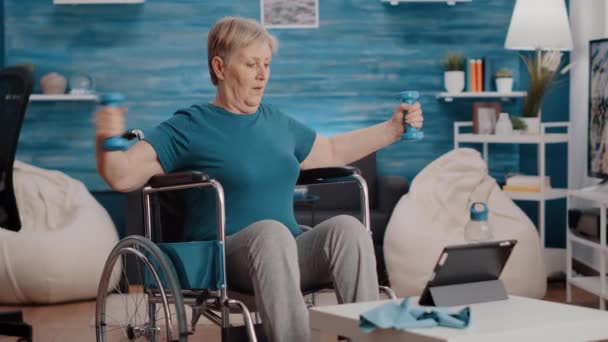 Stará žena protahuje paže svaly s činkami — Stock video