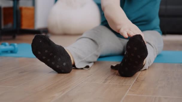 Крупный план пожилого человека, растягивающего руки и ноги на коврике для йоги — стоковое видео